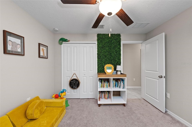 recreation room featuring a textured ceiling, carpet flooring, and a ceiling fan