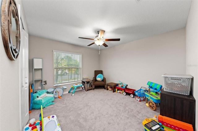 recreation room featuring a textured ceiling, carpet, and a ceiling fan