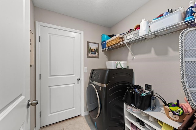 laundry room featuring a textured ceiling, laundry area, light tile patterned flooring, and washer / dryer