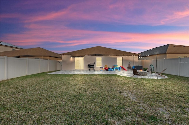 rear view of property with a fire pit, a lawn, and a patio