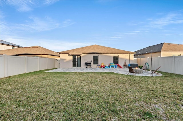 rear view of house featuring a patio area, a yard, and a fire pit