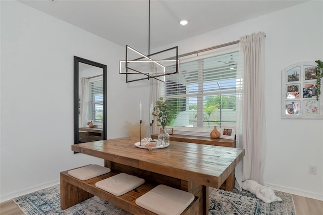 dining area with light wood-type flooring, a notable chandelier, plenty of natural light, and baseboards