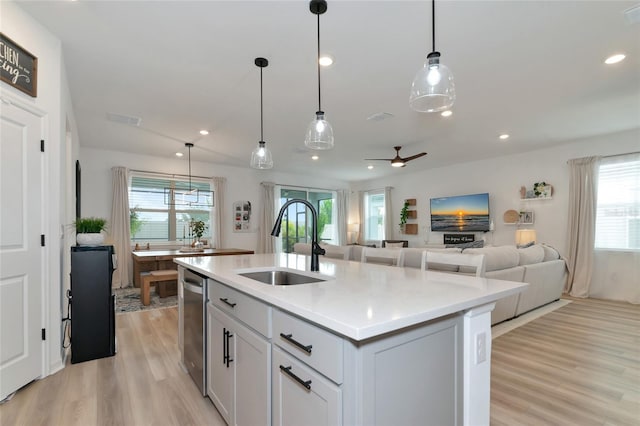 kitchen with a sink, visible vents, light countertops, stainless steel dishwasher, and light wood finished floors