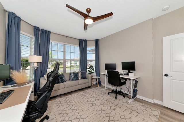 home office with a ceiling fan, light wood-style flooring, and baseboards