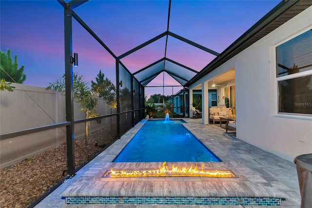 pool at dusk with a fenced in pool, an outdoor living space with a fire pit, a patio, glass enclosure, and fence