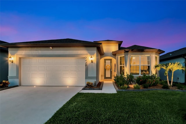 prairie-style home with a garage, concrete driveway, a front lawn, and stucco siding