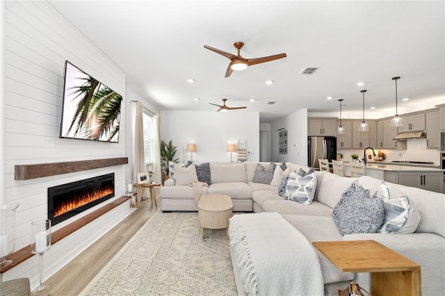 living room featuring visible vents, ceiling fan, light wood-style floors, a fireplace, and recessed lighting