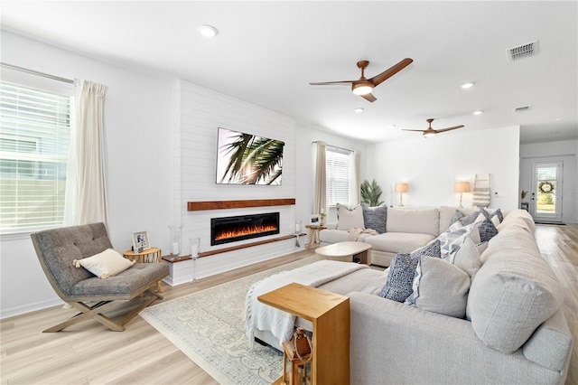 living area with light wood-type flooring, a large fireplace, visible vents, and recessed lighting