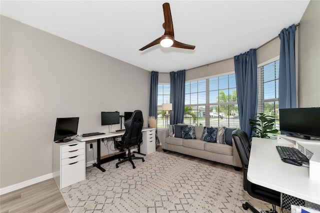 home office featuring light wood finished floors, ceiling fan, and baseboards