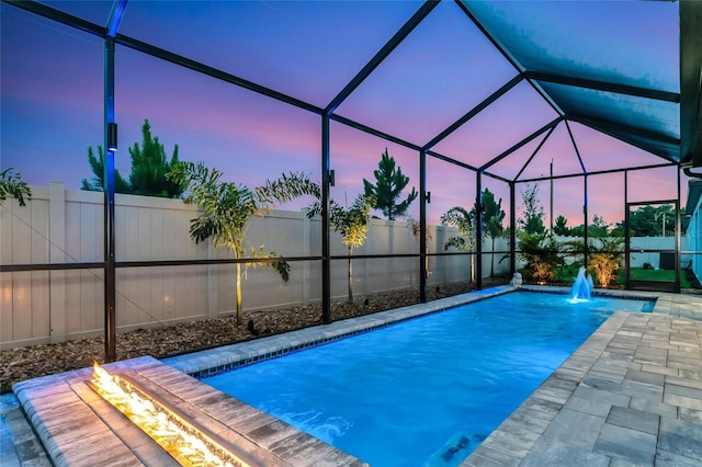 view of swimming pool with a fire pit, glass enclosure, and a fenced backyard