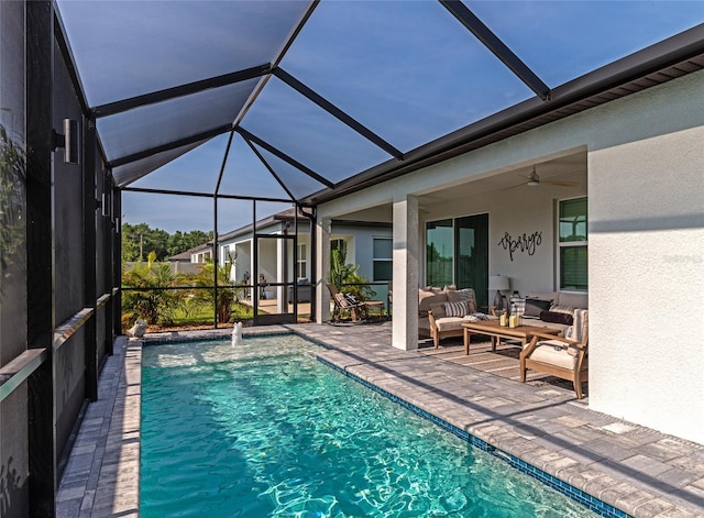 outdoor pool featuring a patio area, glass enclosure, an outdoor hangout area, and a ceiling fan