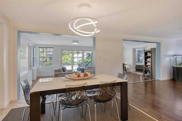 dining space with baseboards, light wood-type flooring, and a notable chandelier