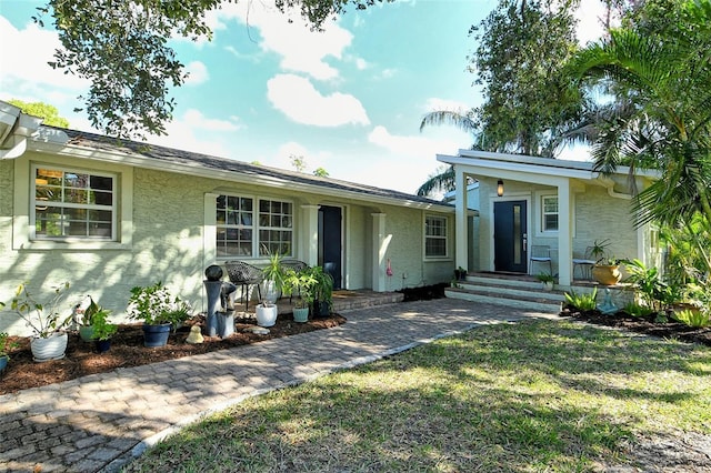 ranch-style house featuring a front lawn and stucco siding