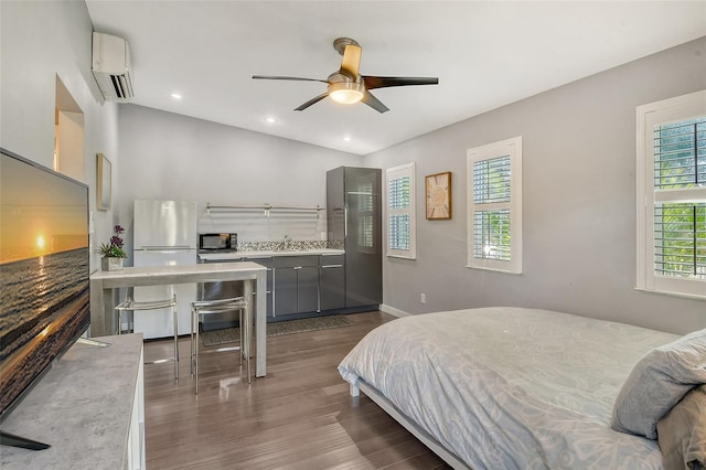 bedroom with white refrigerator, sink, a wall unit AC, and dark hardwood / wood-style floors