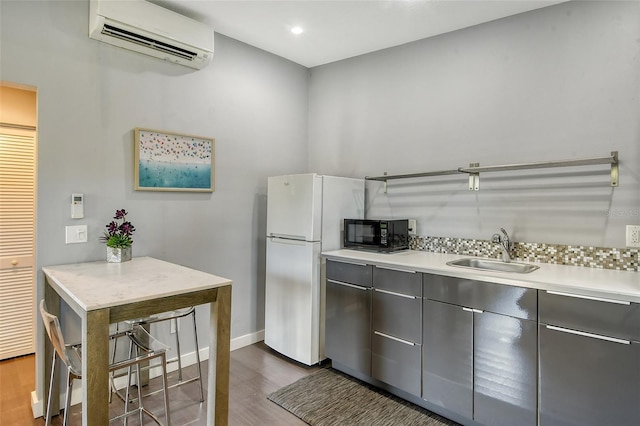 kitchen with dark hardwood / wood-style flooring, sink, a wall mounted AC, and white refrigerator