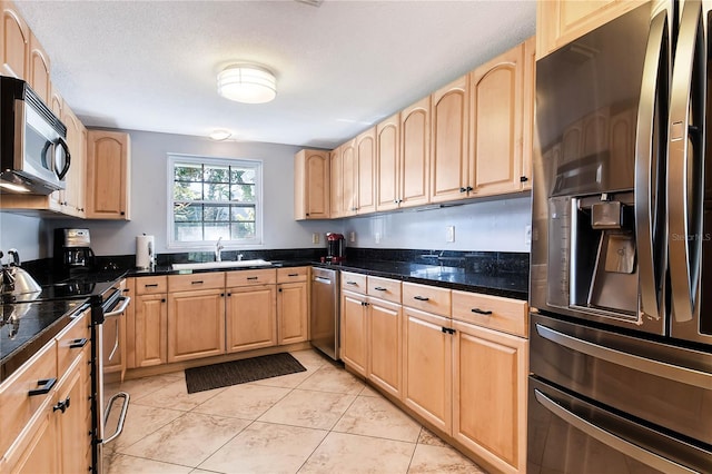 kitchen with stainless steel appliances, light brown cabinets, a sink, and light tile patterned floors