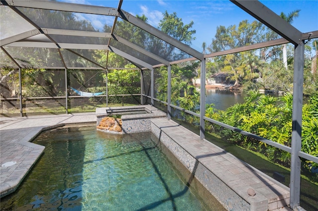 outdoor pool featuring a patio area, glass enclosure, a water view, and an in ground hot tub