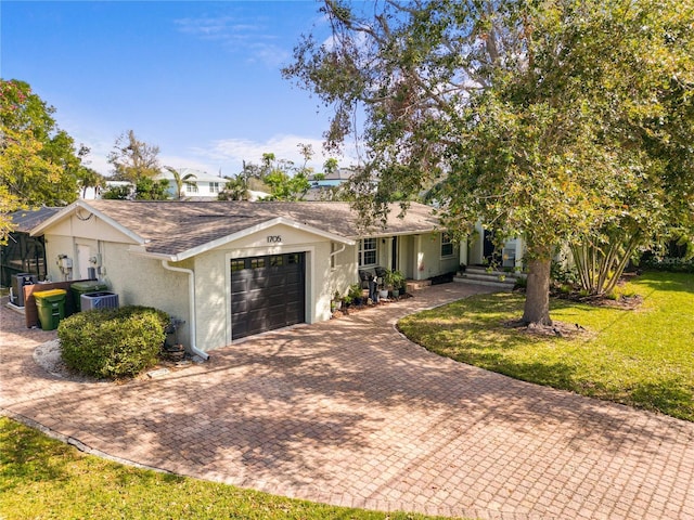 single story home with an attached garage, a shingled roof, decorative driveway, stucco siding, and a front yard