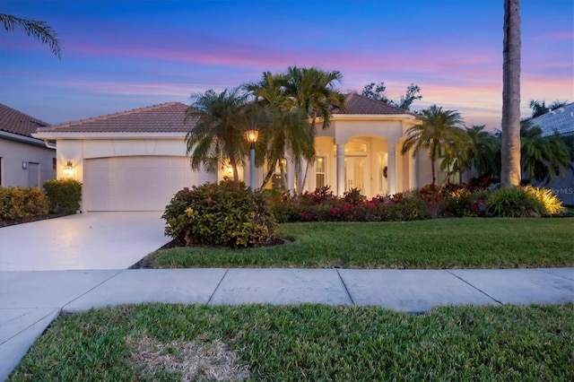 mediterranean / spanish-style home with a garage and a lawn