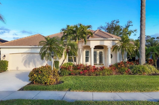 mediterranean / spanish home featuring a garage, a front lawn, and french doors