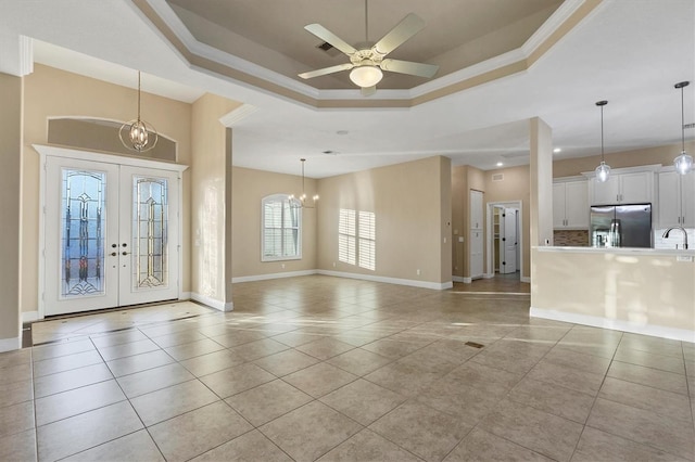 tiled entryway with sink, a tray ceiling, ceiling fan with notable chandelier, and french doors