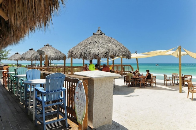 view of patio featuring a gazebo, a deck with water view, and a beach view