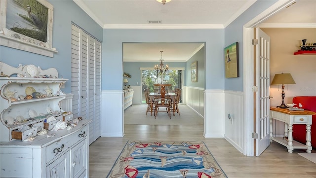 hall featuring crown molding, a chandelier, and light hardwood / wood-style flooring