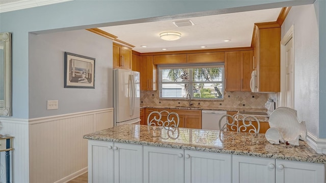 kitchen with light stone counters, white appliances, white cabinetry, and sink