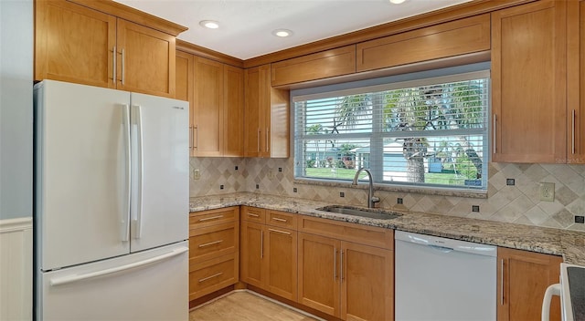 kitchen with sink, light stone counters, white appliances, and decorative backsplash