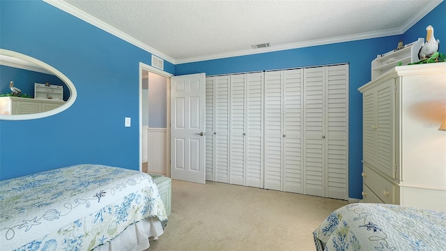 carpeted bedroom with crown molding, a closet, and a textured ceiling