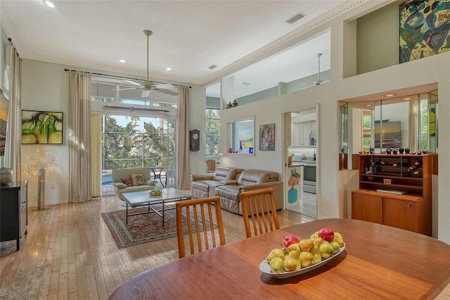 dining space with ceiling fan, a towering ceiling, and light wood-type flooring