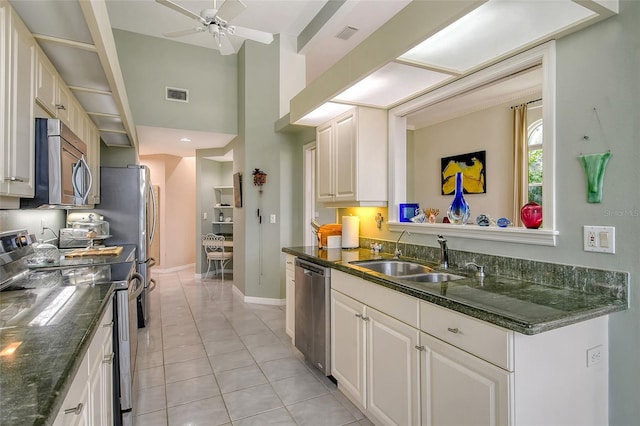 kitchen featuring sink, light tile patterned floors, ceiling fan, stainless steel appliances, and white cabinets