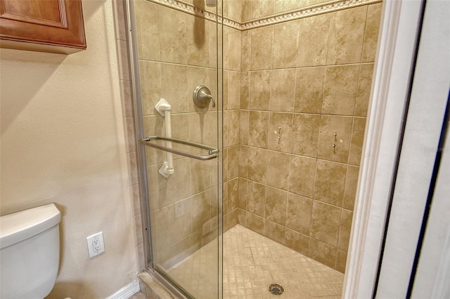 bathroom featuring toilet and a shower with shower door