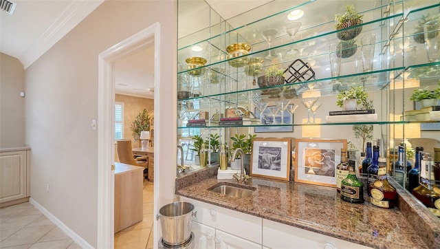 bar featuring stone countertops, sink, light tile patterned floors, and white cabinets