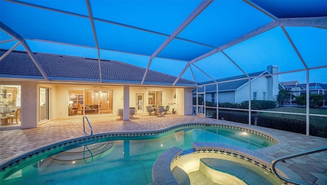 view of pool with an in ground hot tub, a patio area, ceiling fan, and glass enclosure