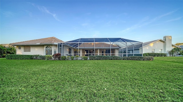 rear view of property featuring a lanai and a lawn