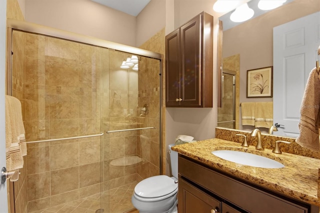 bathroom featuring vanity, toilet, and a shower with shower door