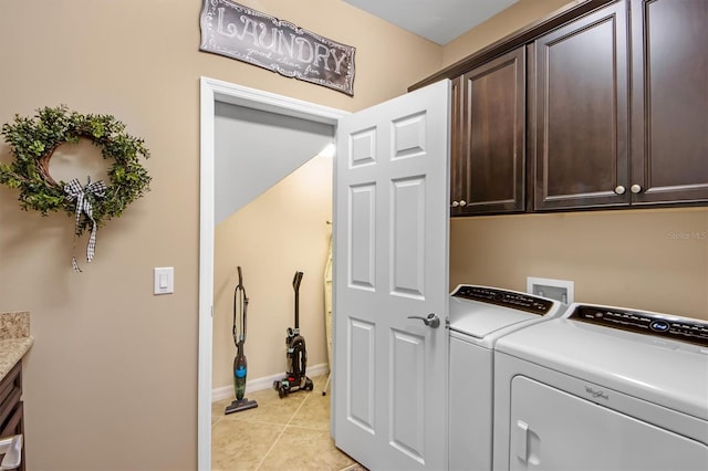 clothes washing area featuring cabinets, washing machine and dryer, and light tile patterned floors