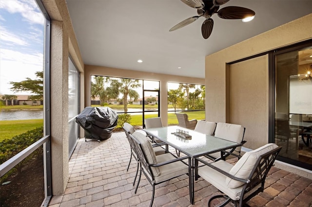 sunroom / solarium featuring a water view and ceiling fan