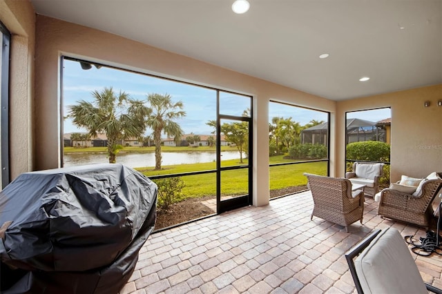 sunroom featuring a water view