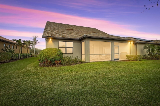 back house at dusk with a lawn