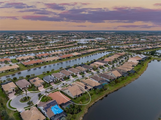 aerial view at dusk featuring a water view