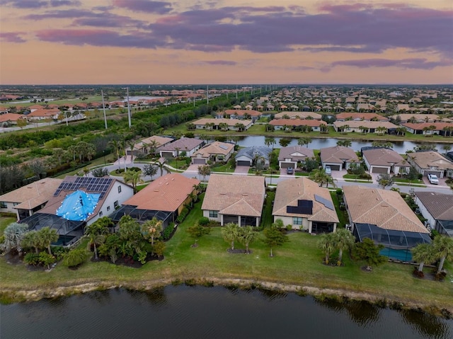 aerial view at dusk featuring a water view