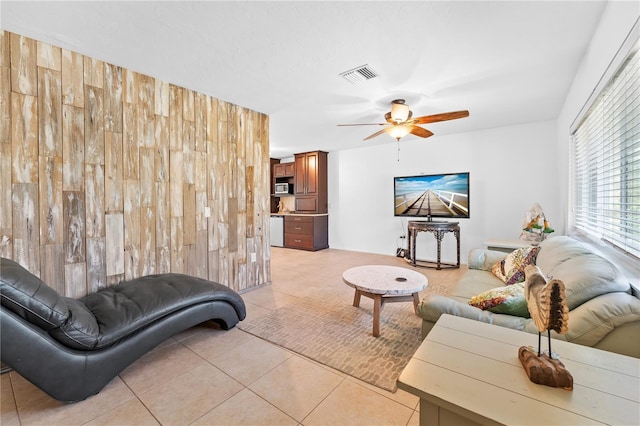 tiled living room featuring wooden walls and ceiling fan