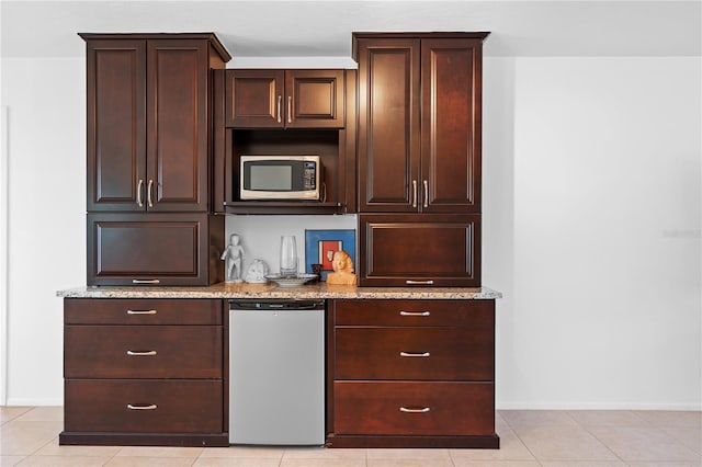 bar featuring fridge, dark brown cabinets, light stone counters, and light tile patterned floors