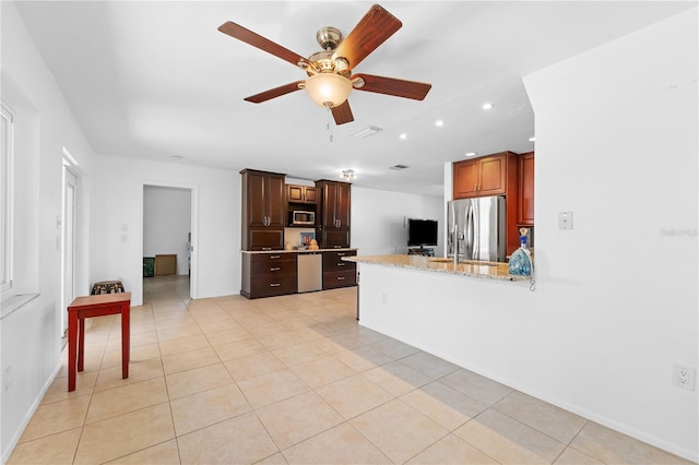 kitchen featuring light stone counters, stainless steel appliances, kitchen peninsula, and light tile patterned floors