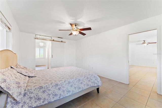 tiled bedroom with ceiling fan and a barn door