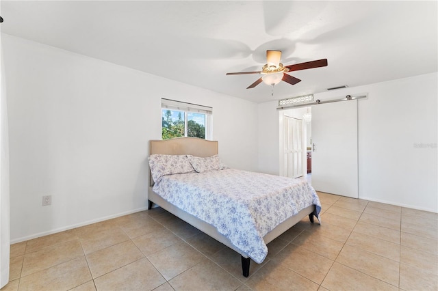 bedroom featuring light tile patterned floors, a barn door, and ceiling fan