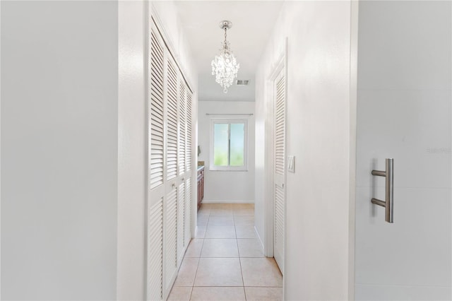 hall featuring light tile patterned floors and a notable chandelier