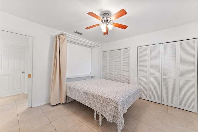 tiled bedroom featuring ceiling fan and two closets